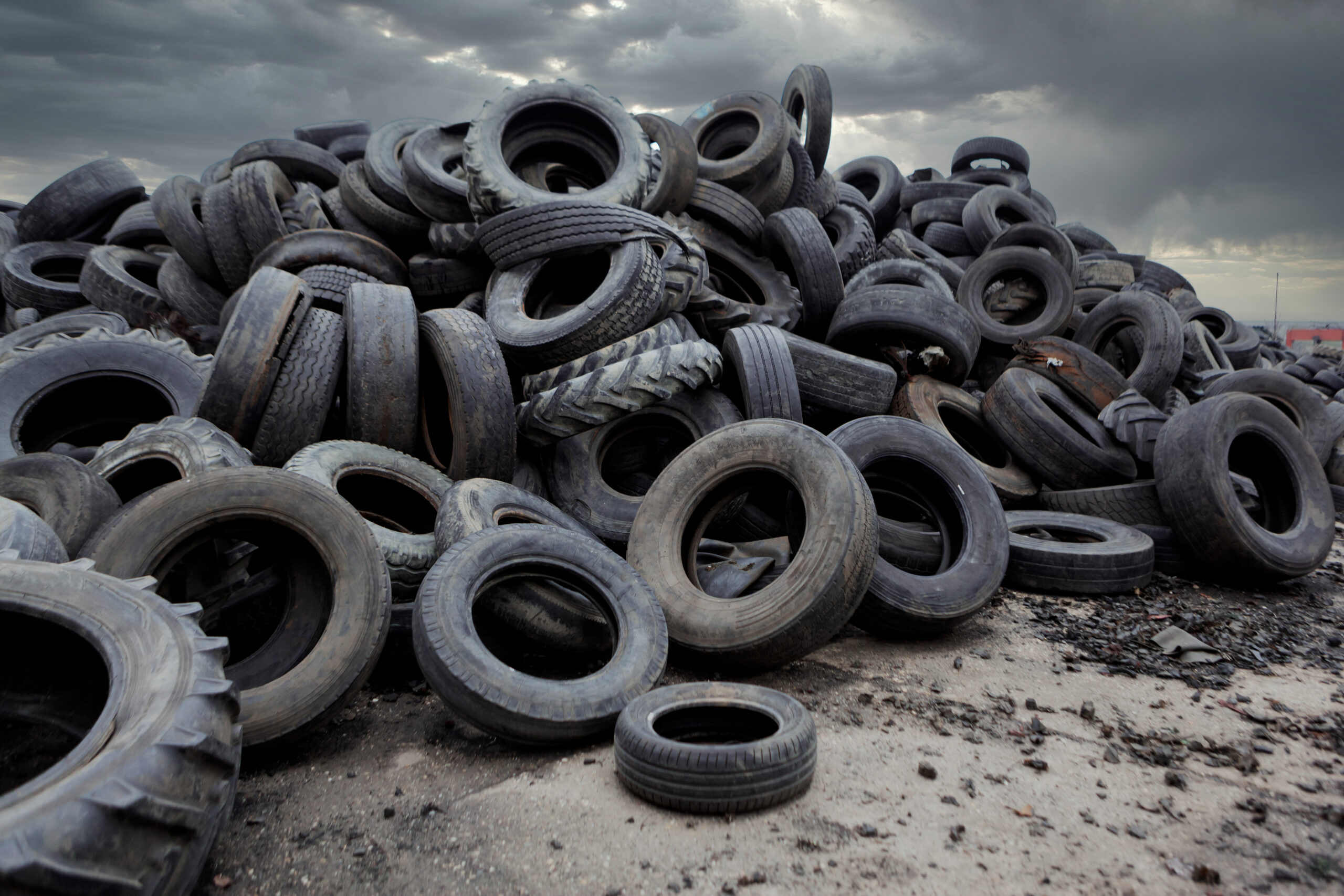 Industrial landfill for the processing of waste tires and rubber tyres. Pile of old tires and wheels for rubber recycling. Tyre dump